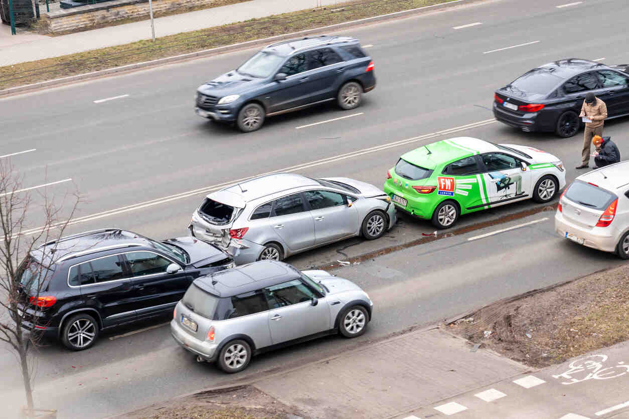 Damaged vehicles involved in a deadly multi-car collision on Capital Boulevard in Wake Forest, with police officers documenting the accident scene after a wrong-way driver incident.