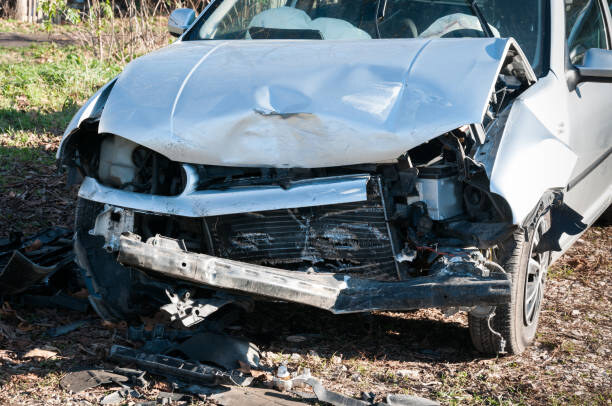 Front view of a severely damaged silver car involved in a fatal car crash, symbolizing the tragic accident that led to the death of UNC strength coach Nick Vetell.