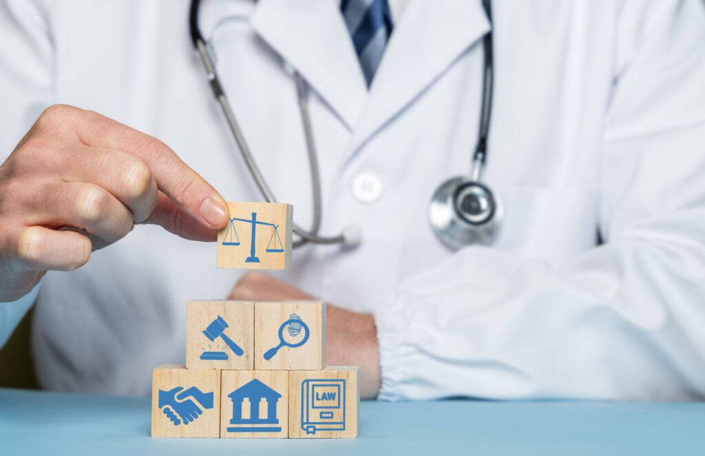 Medical professional stacking blocks with legal and justice symbols, representing the medical and legal intersection of Maximum Medical Improvement (MMI) in North Carolina workers' compensation claims.