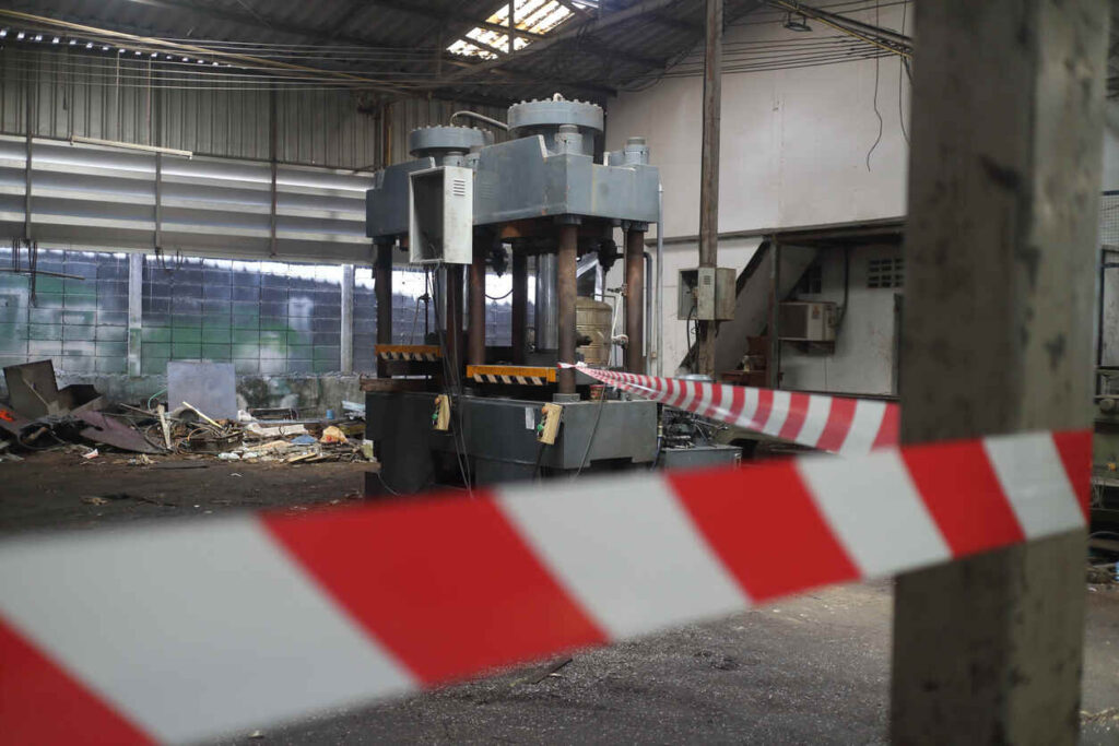 Scene of a workplace incident at a Kings Mountain manufacturing site, showing a heavy-duty press machine surrounded by safety tape, after a fatal accident involving a Gastonia man.