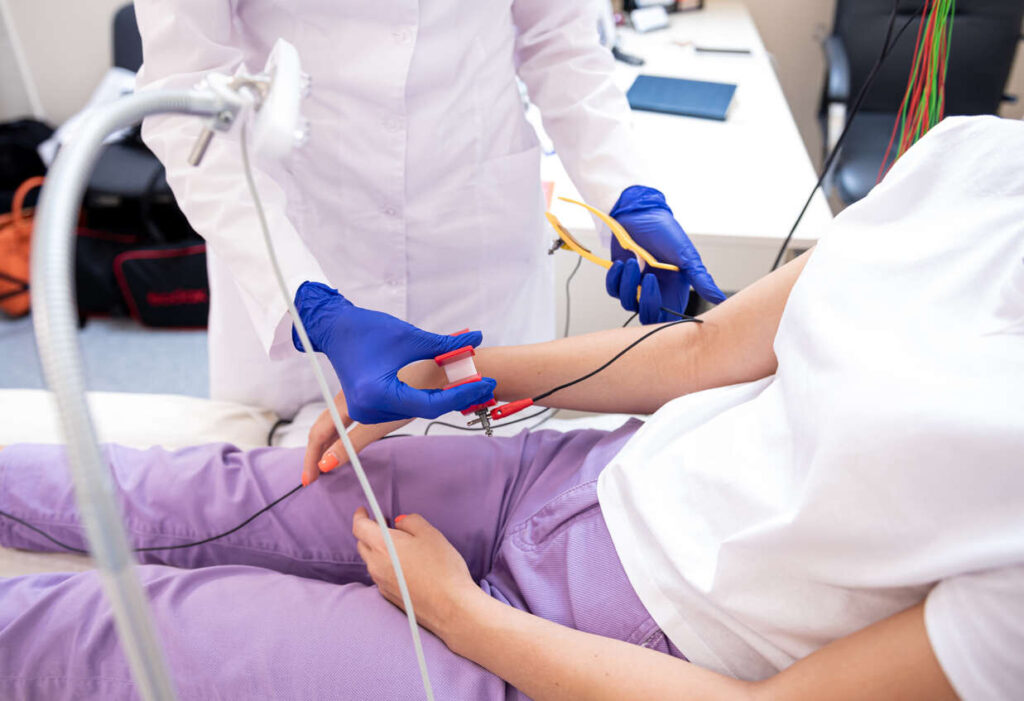 Medical professional attaching electrodes to a patient's arm for peripheral nerve stimulation.