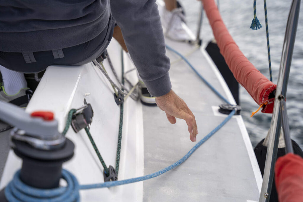 Hand on sailboat deck with ropes and winches