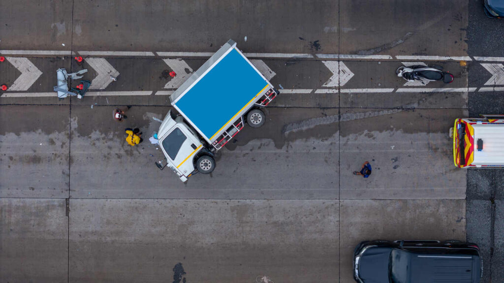 Aerial view of a truck and emergency responders at the scene of a fatal highway accident.